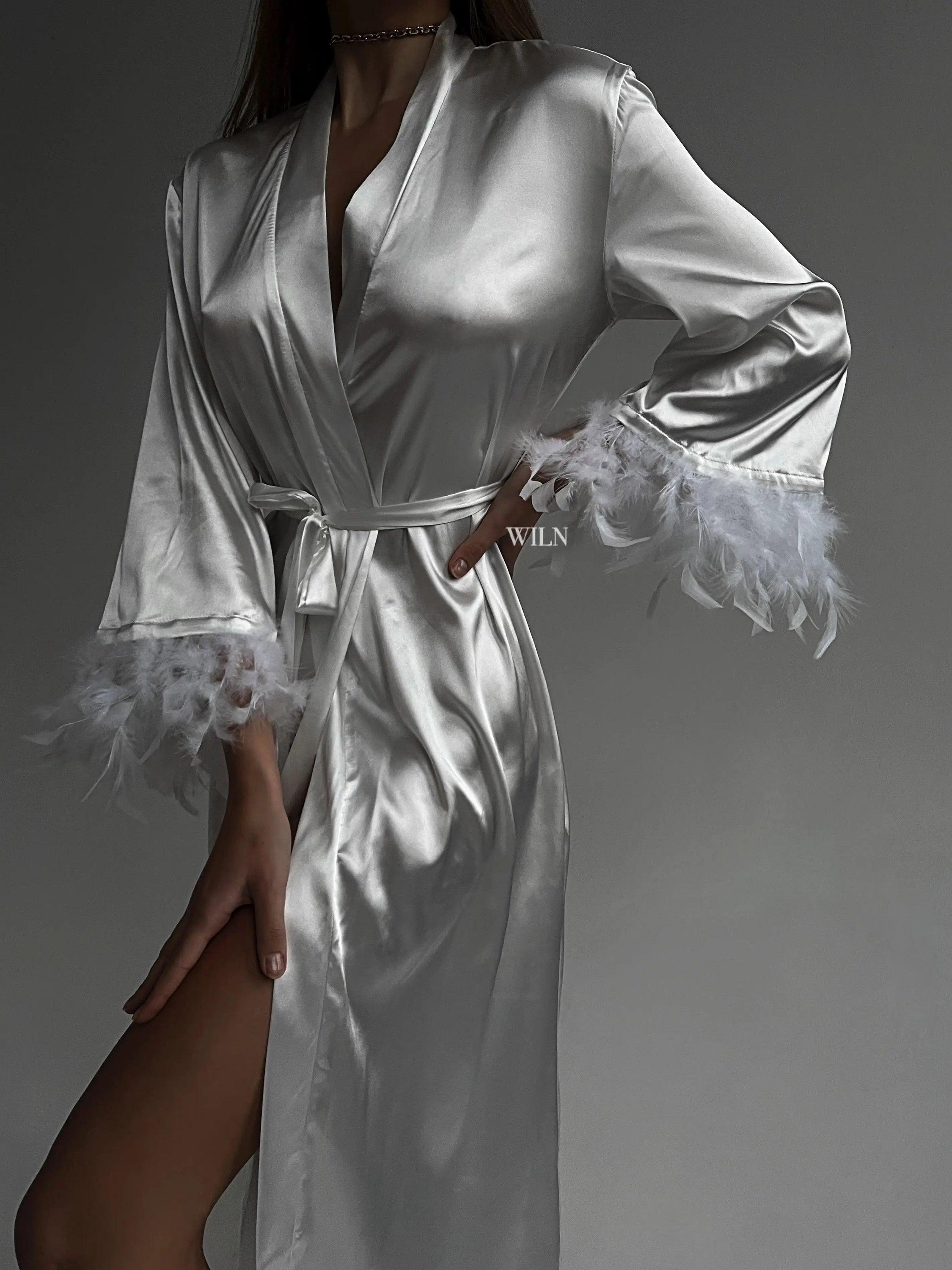 A luxurious white satin robe with flowy long sleeves and feather trim, perfect for bridal occasions.