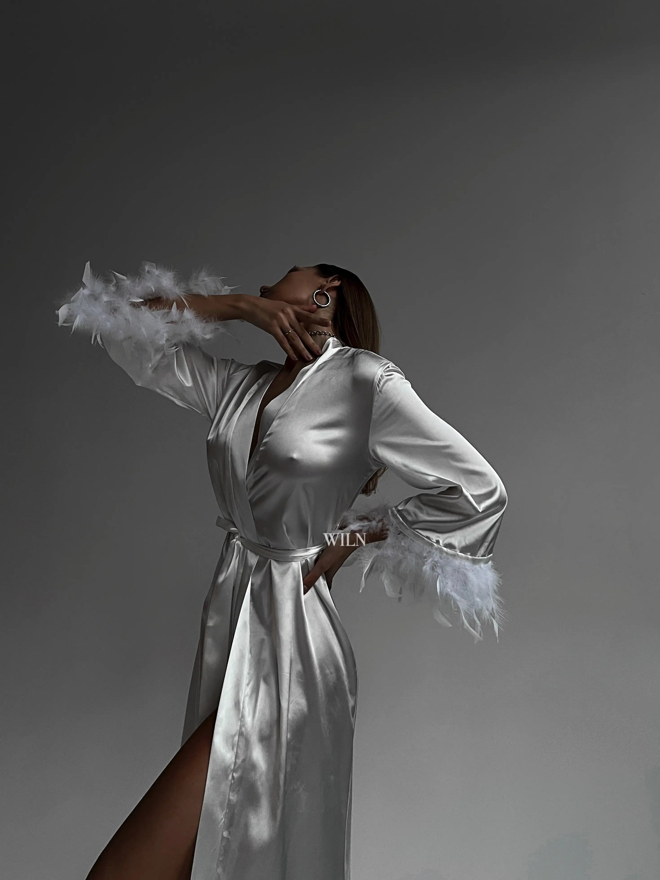 A luxurious white satin robe with flowy long sleeves and feather trim, perfect for bridal occasions.