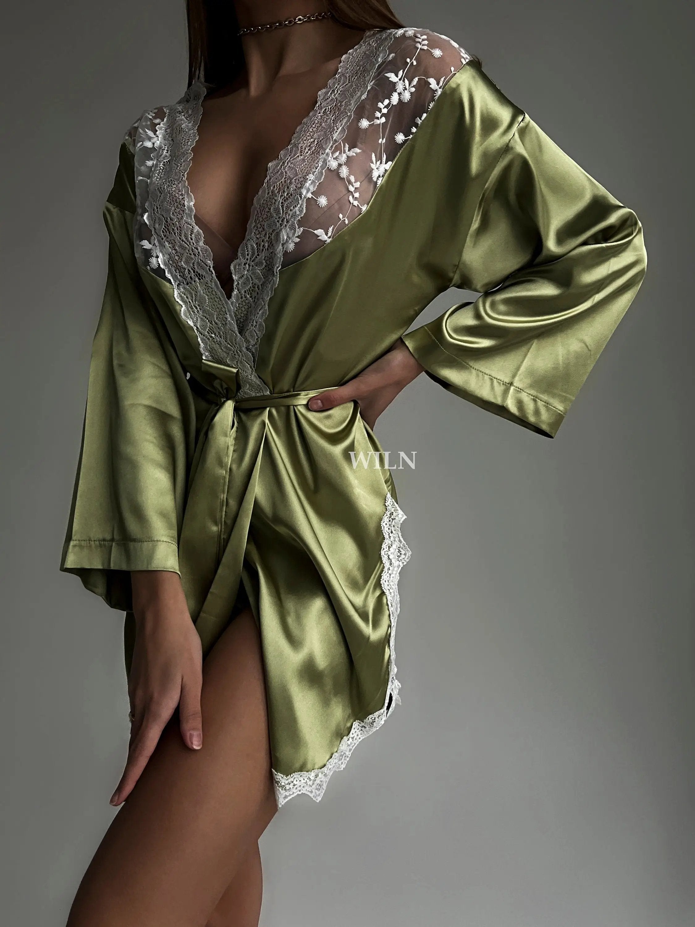 A luxurious green satin robe with flowy long sleeves and lace trim, perfect for brides and special occasions.