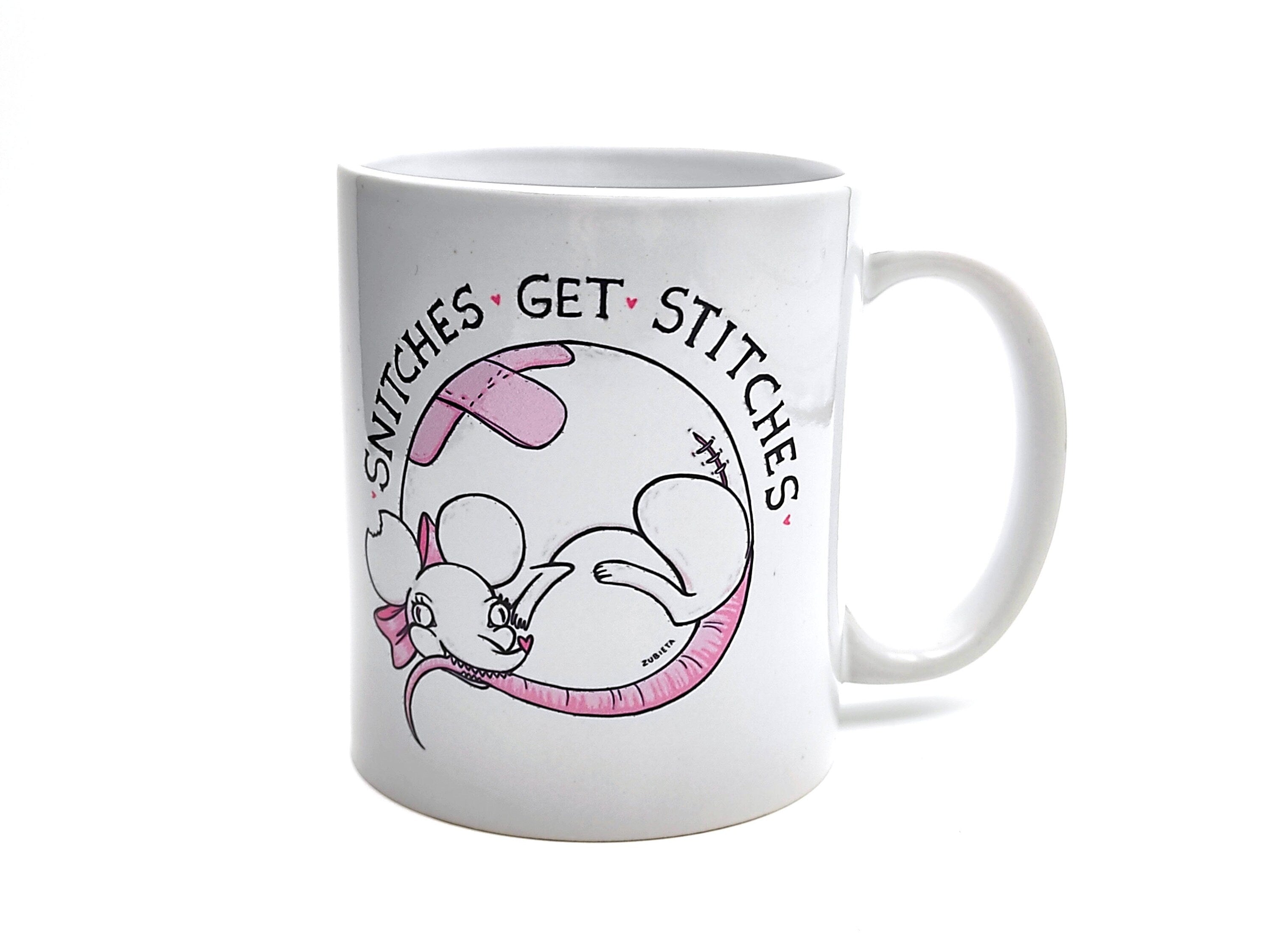 Ceramic mug featuring the phrase 'Snitches Get Stitches' with a cute evil design, perfect for coffee or tea lovers.