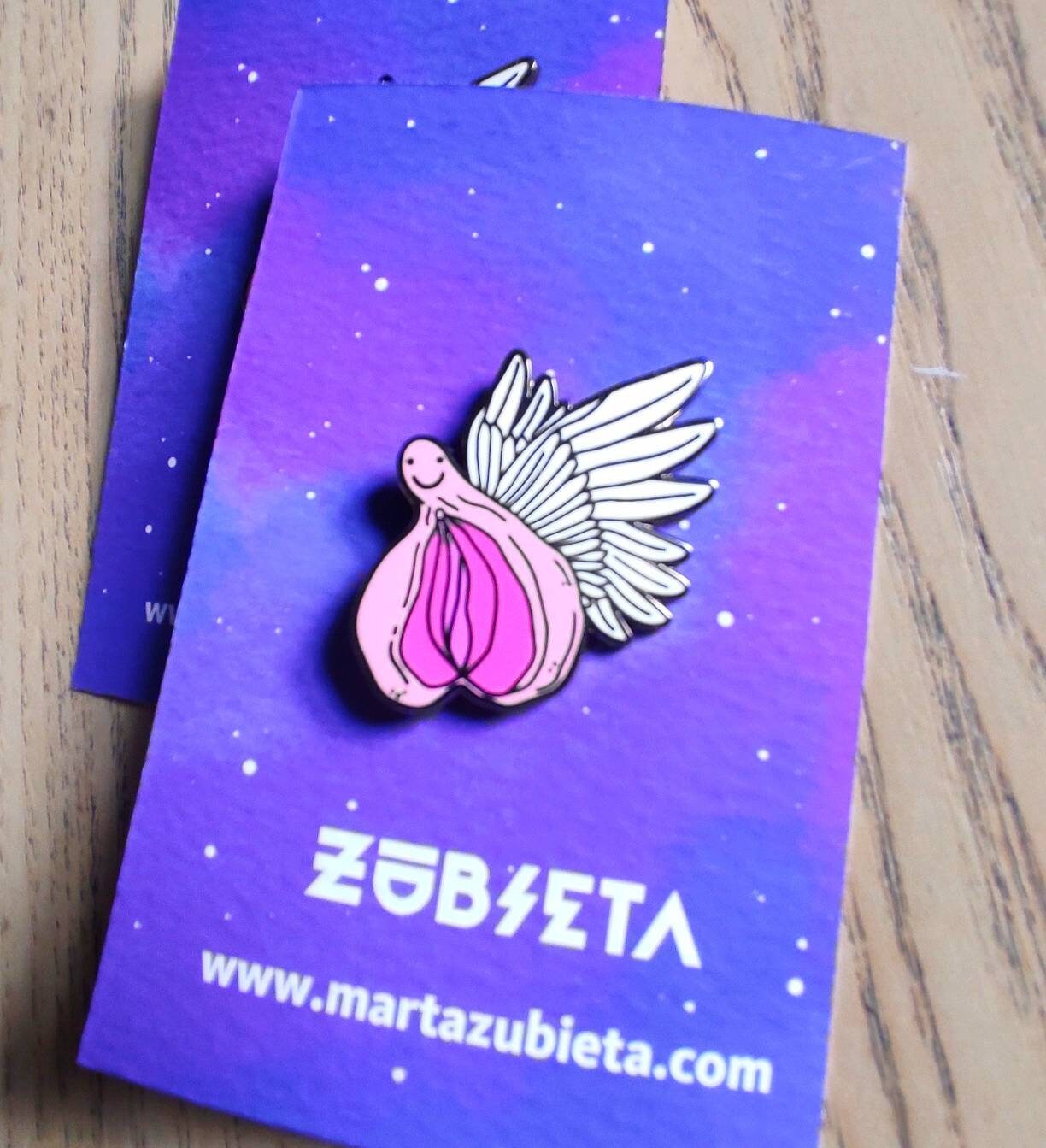 A colorful enamel pin featuring a whimsical design of flying vaginas in space, symbolizing body positivity and empowerment.