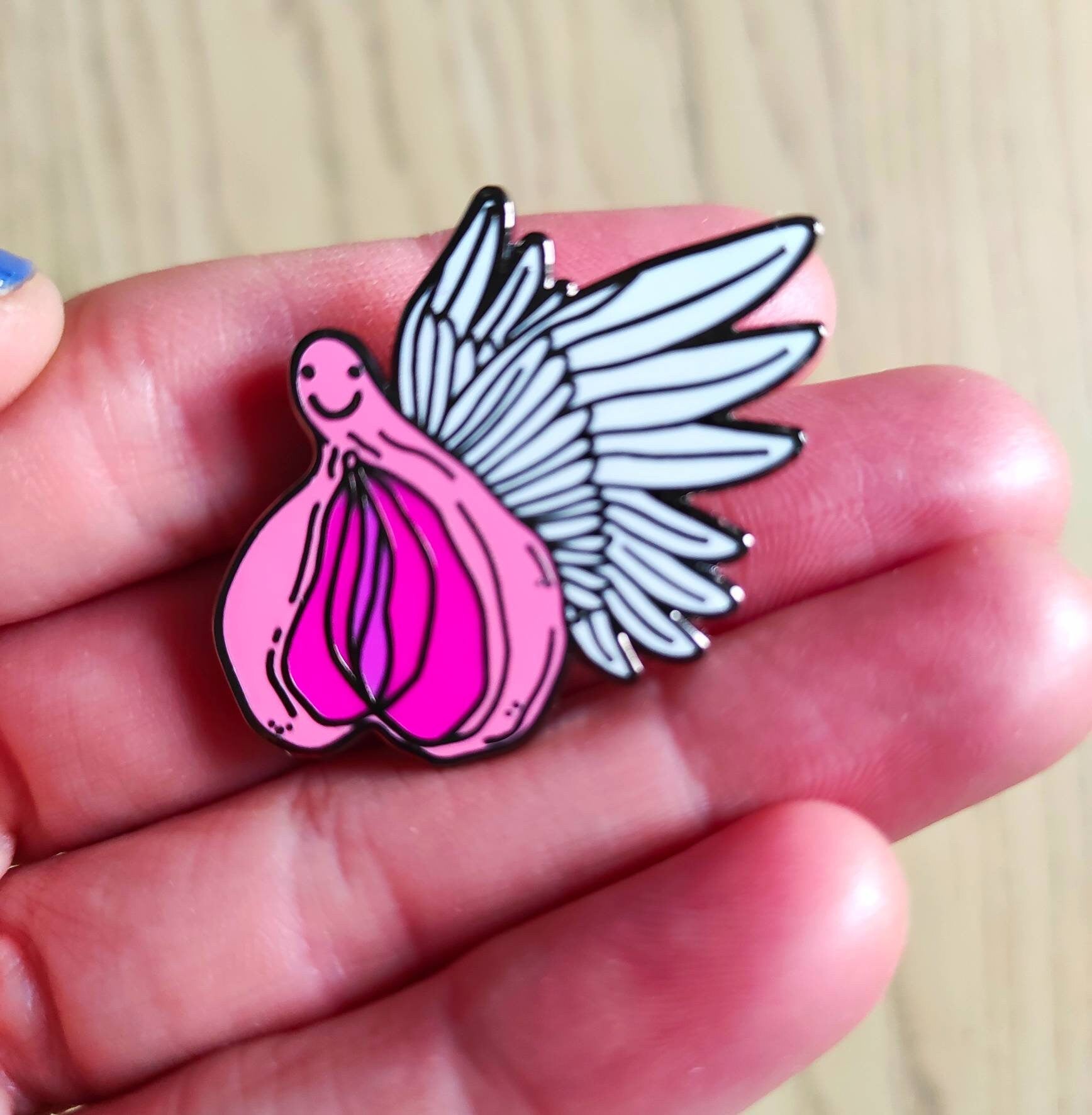 A colorful enamel pin featuring a whimsical design of flying vaginas in space, symbolizing body positivity and empowerment.