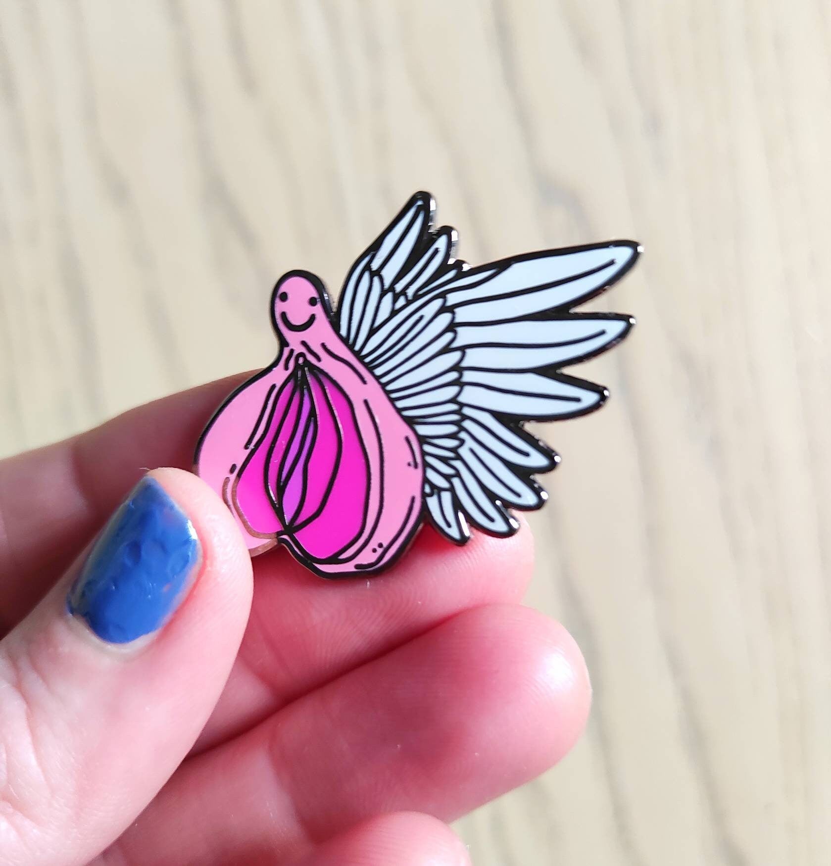 A colorful enamel pin featuring a whimsical design of flying vaginas in space, symbolizing body positivity and empowerment.