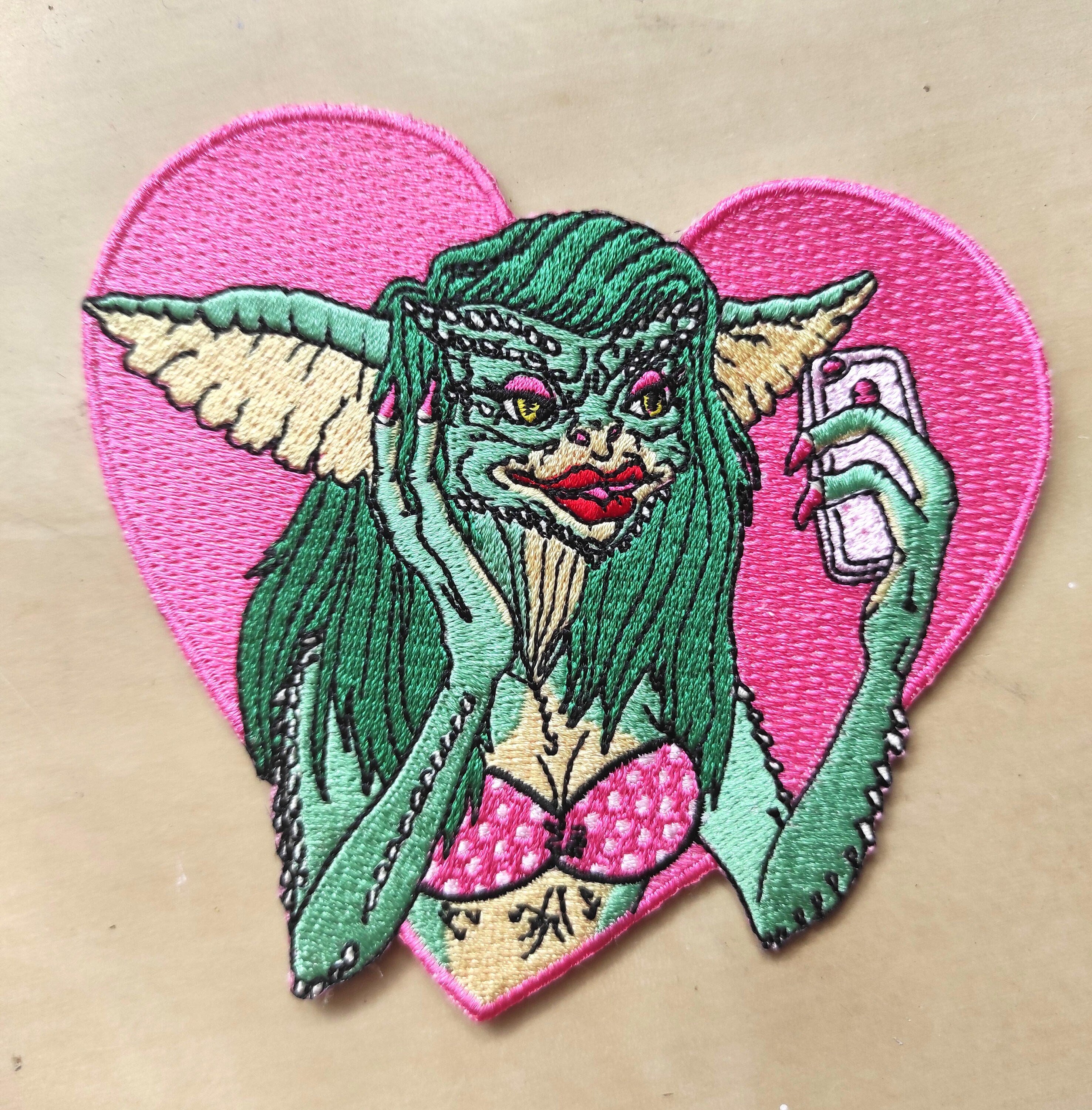 Greta The Gremlin Embroidered Patch featuring vibrant colors and playful design, measuring 12.5cm x 12.5cm.