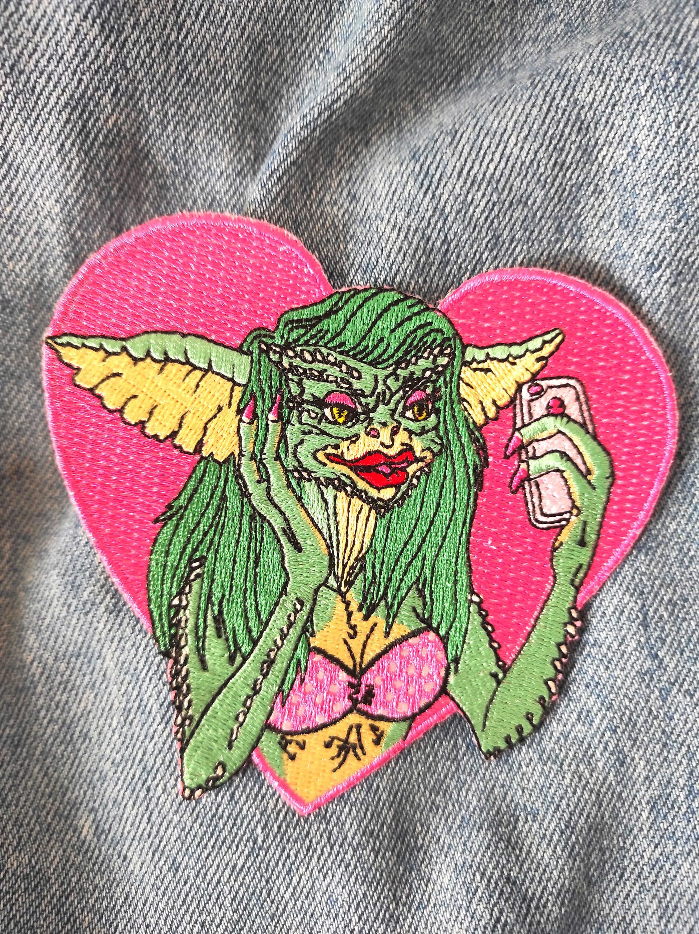 Greta The Gremlin Embroidered Patch featuring vibrant colors and playful design, measuring 12.5cm x 12.5cm.