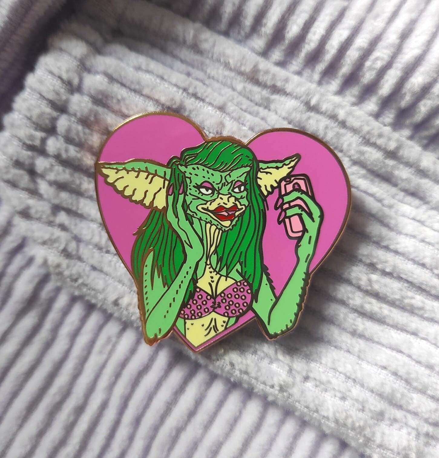 Greta the Gremlin Maxi Pin featuring a cute and creepy design, 2 inches wide, made of hard enamel with a rose gold metal finish.