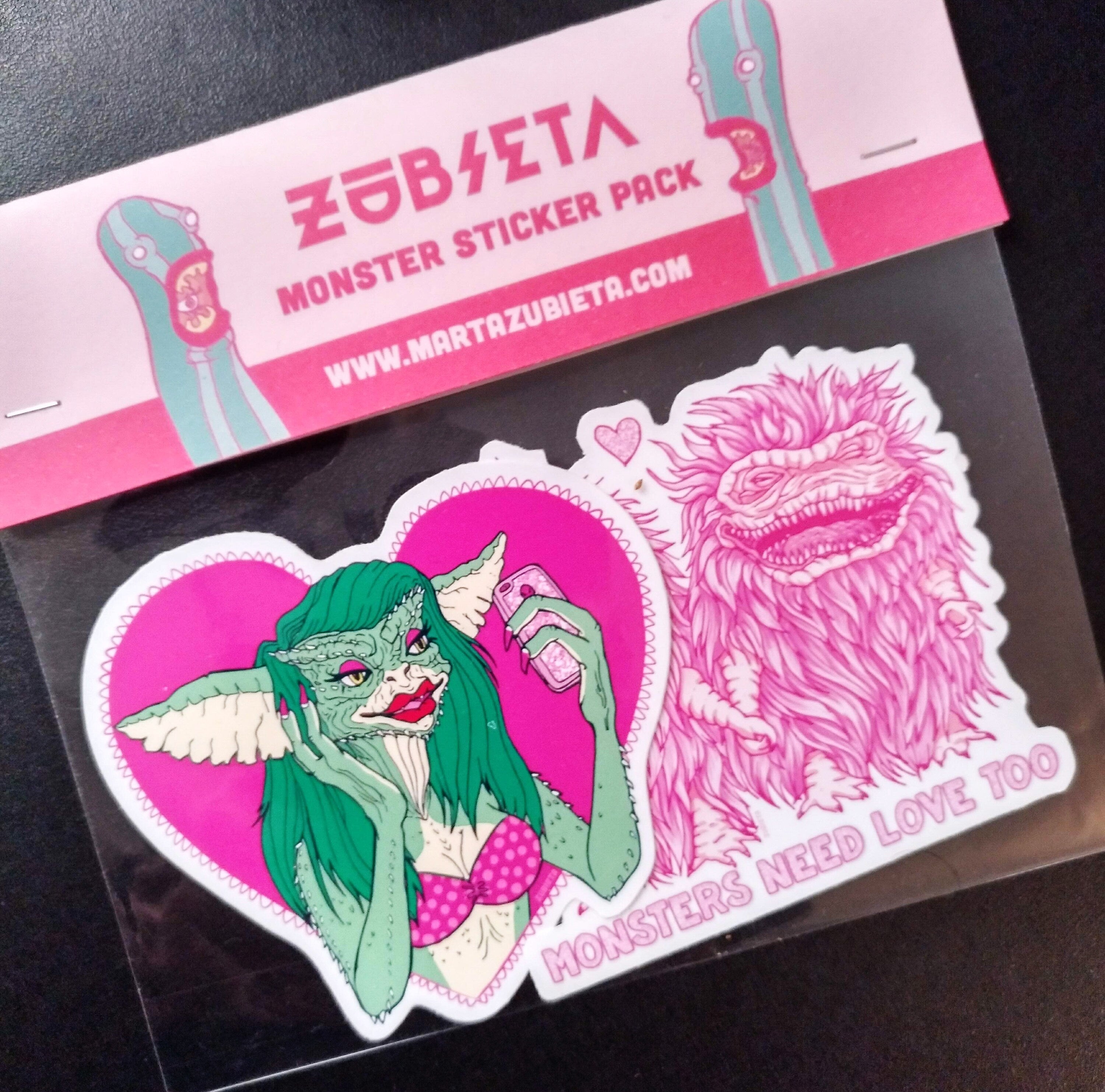 A pack of two colorful vinyl stickers featuring Greta the Gremlin and the phrase Monsters Need Love Too, perfect for 80's horror movie fans.