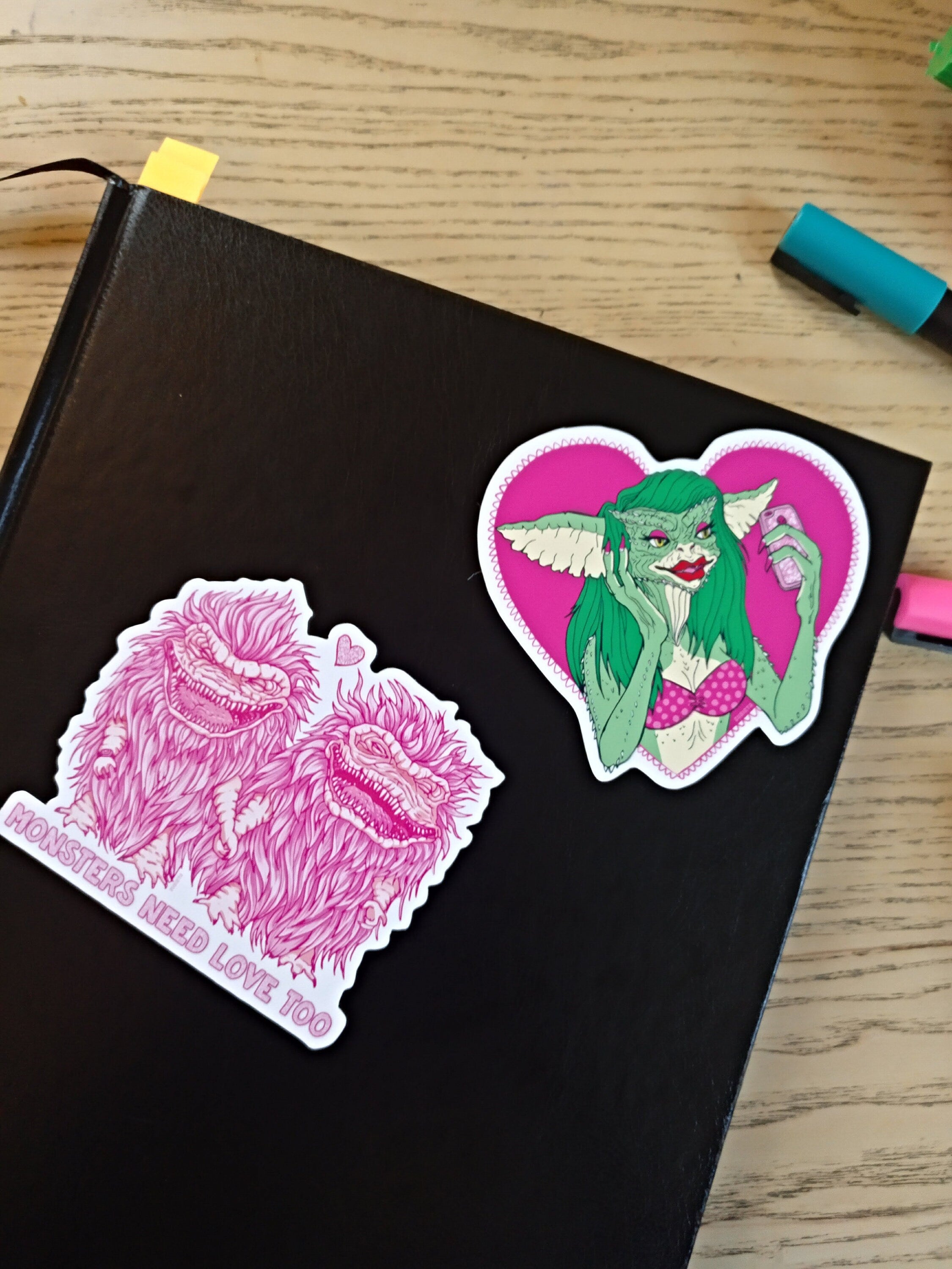 A pack of two colorful vinyl stickers featuring Greta the Gremlin and the phrase Monsters Need Love Too, perfect for 80's horror movie fans.