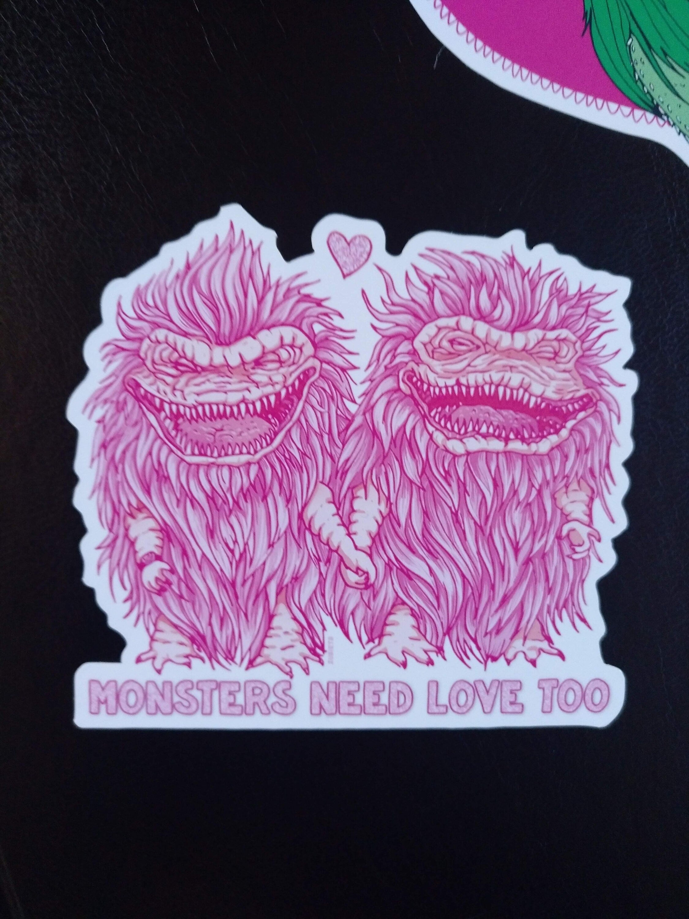 A pack of two colorful vinyl stickers featuring Greta the Gremlin and the phrase Monsters Need Love Too, perfect for 80's horror movie fans.