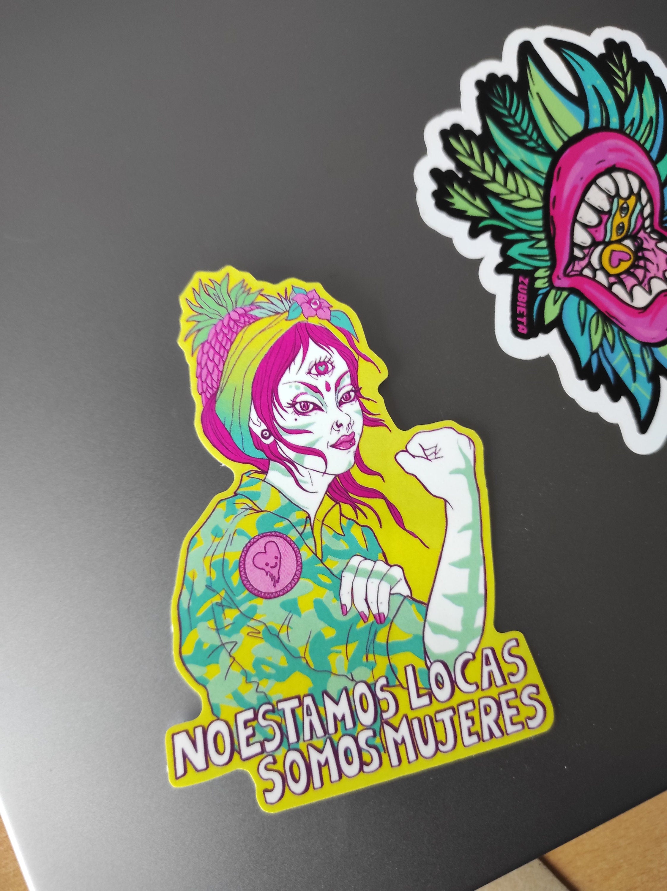 A vibrant Rosie The Riveter sticker featuring the phrase 'No estamos locas! Somos Mujeres!' celebrating women's empowerment.