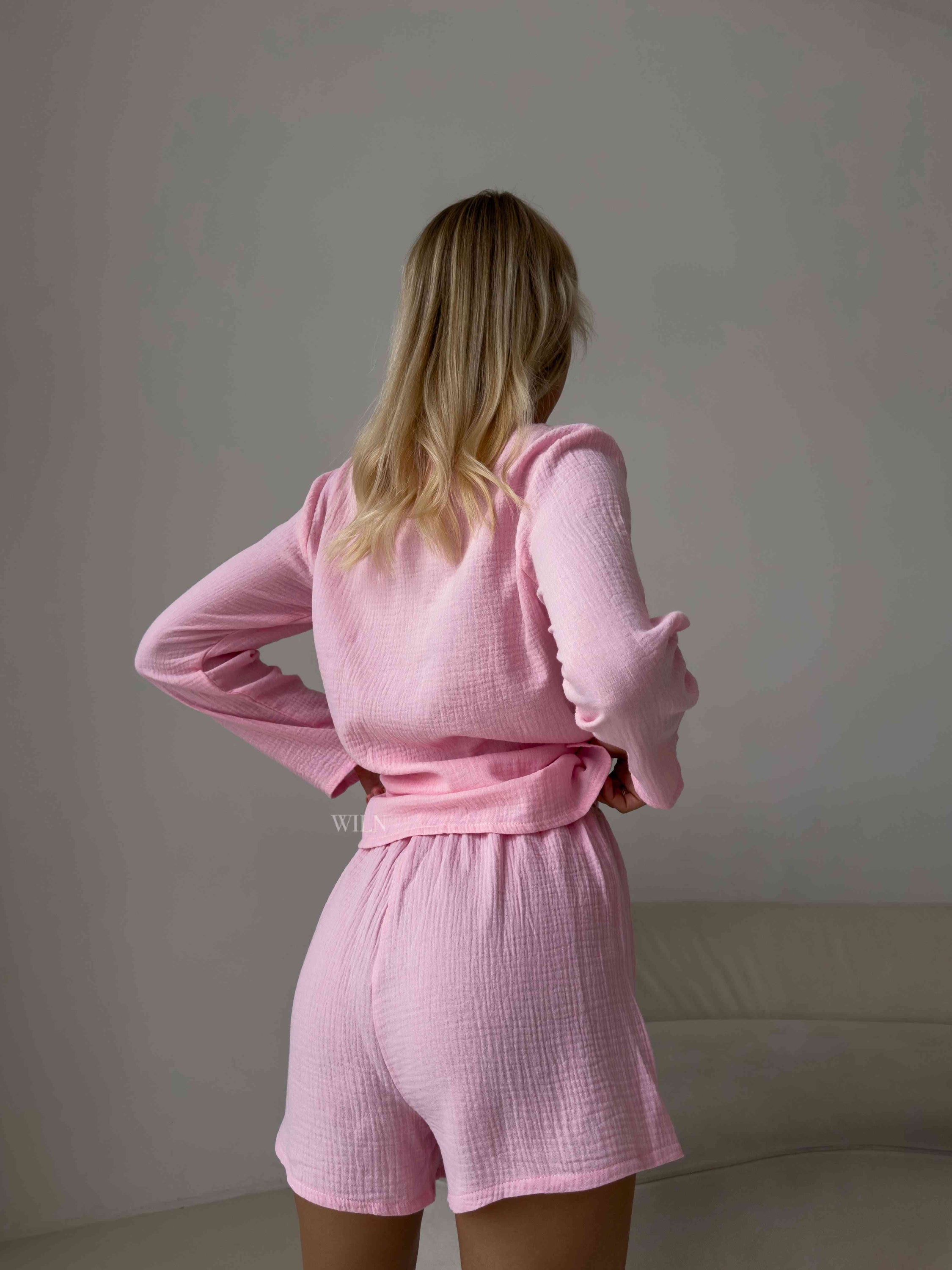 A luxurious pink two-piece lounge set made of soft cotton, featuring a deep plunging neckline and matching bottoms with an elasticated waistband.