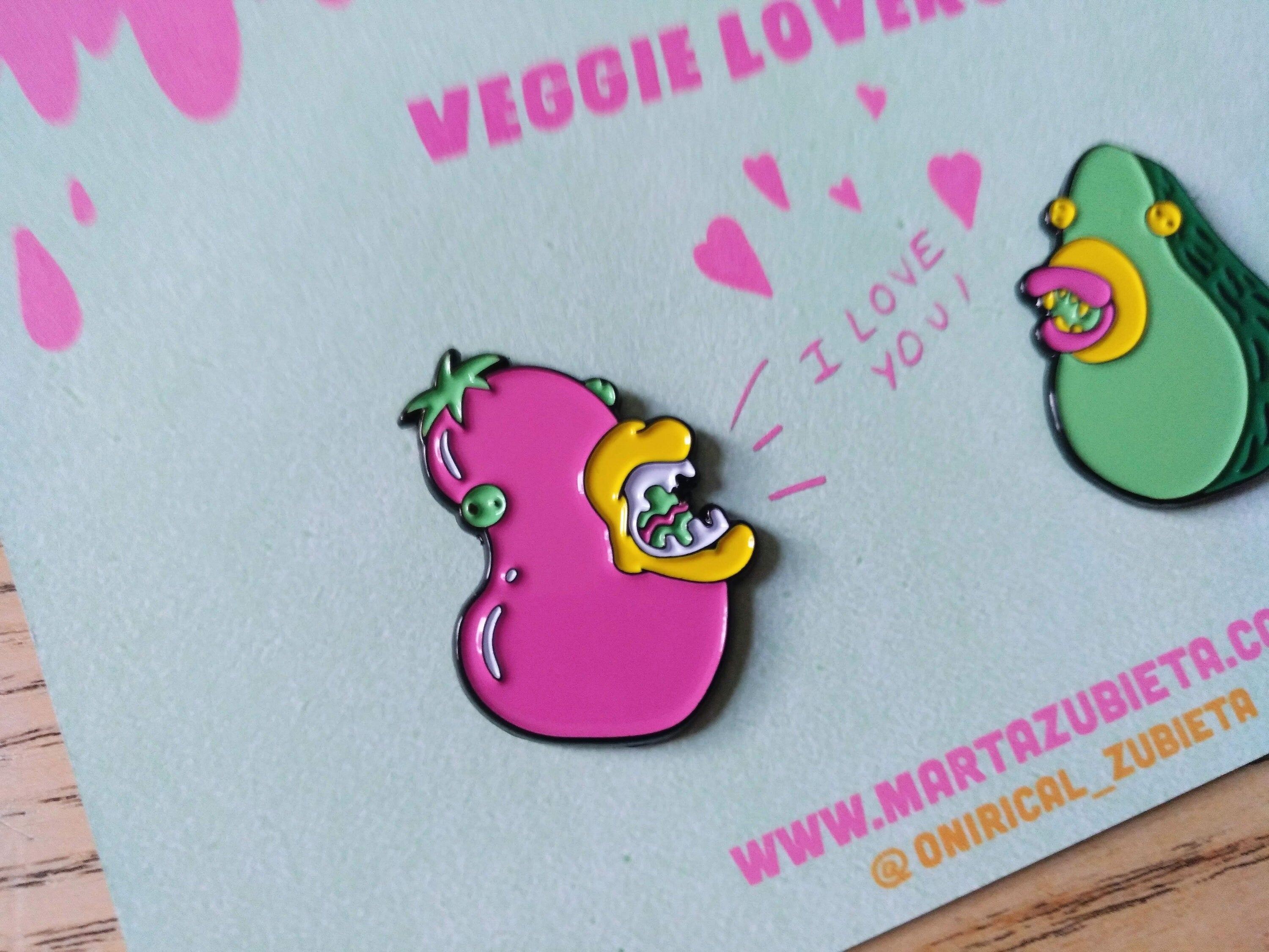 A colorful enamel pin pack featuring avocado and aubergine designs, made from black metal with soft enamel colors.