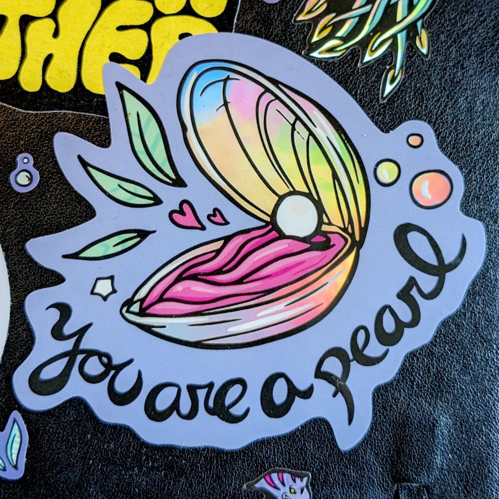 You Are a Pearl Holographic Vinyl Sticker featuring an oyster shell design with a shimmering holographic finish.