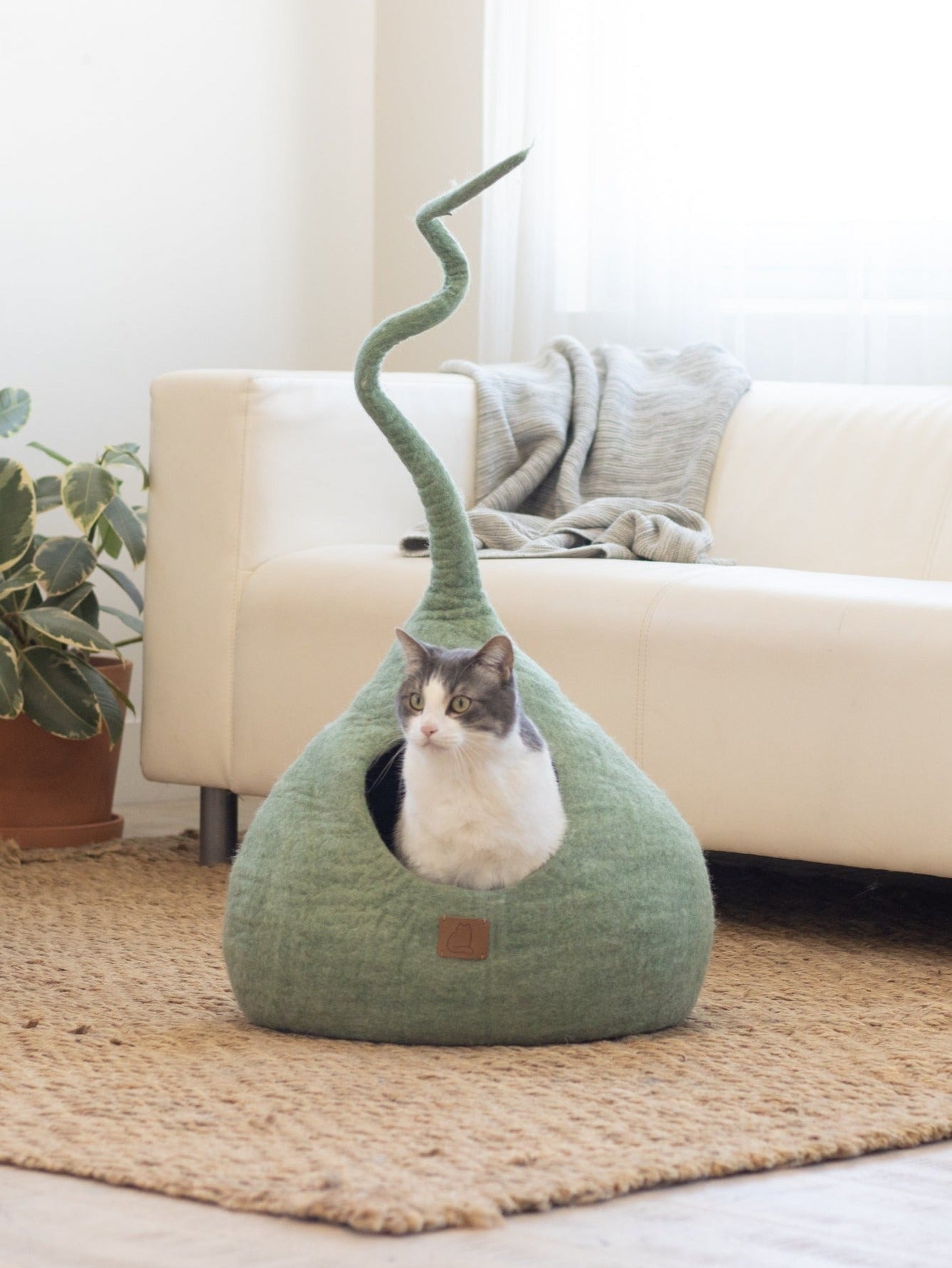 Eucalyptus Green Tail Style Cave, a cozy and stylish cat bed with a peekaboo entrance, handcrafted from felted wool.