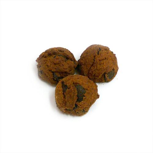 A close-up of freshly baked carob chip cookies with a golden-brown color, featuring visible carob chips and a soft texture, arranged on a rustic wooden surface.