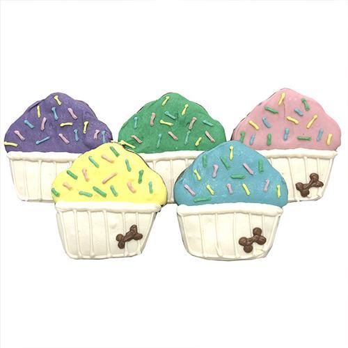 A colorful assortment of larger cupcake treats made with carob and peanut butter, topped with yogurt coating and vegetable coloring, displayed in a case.