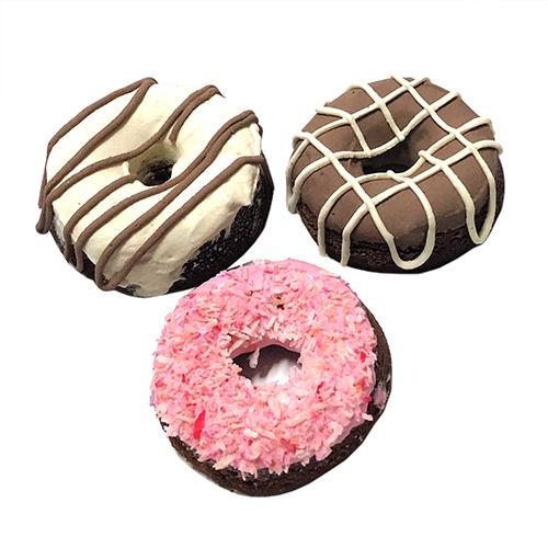 A colorful donut gift box containing four soft peanut butter apple cake donuts for dogs, topped with yogurt coating.