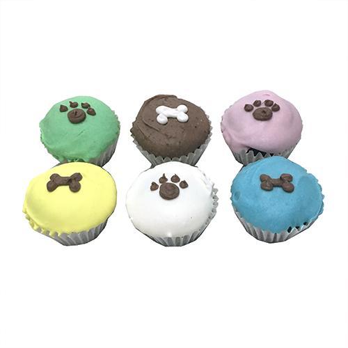 A box containing two mini cupcakes for dogs, made with peanut butter and apple cake, featuring a yogurt coating and colorful vegetable coloring.