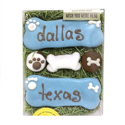 A beautifully arranged Wish You Were Here Box containing five custom dog bones, decorated with colorful icing and personalized names.