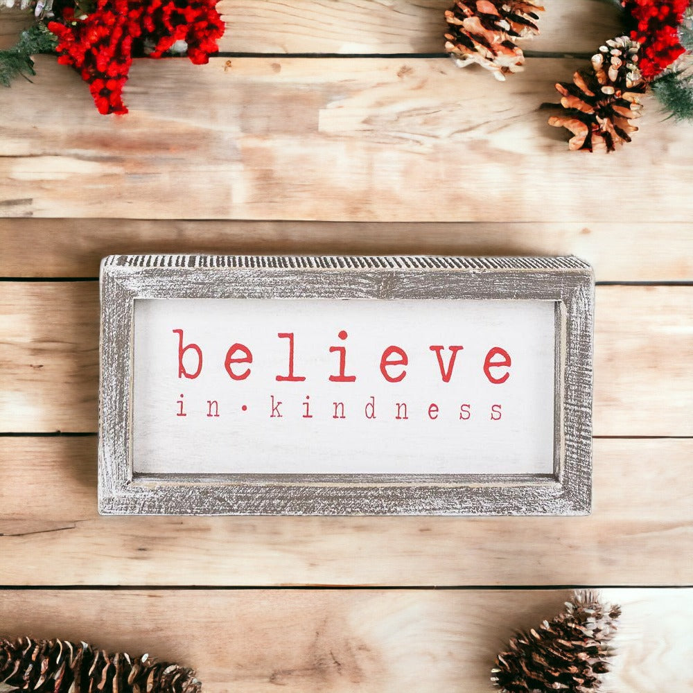 A wood framed Believe Sign featuring the phrase 'Believe In Kindness' in festive white and red colors, perfect for Christmas decor.