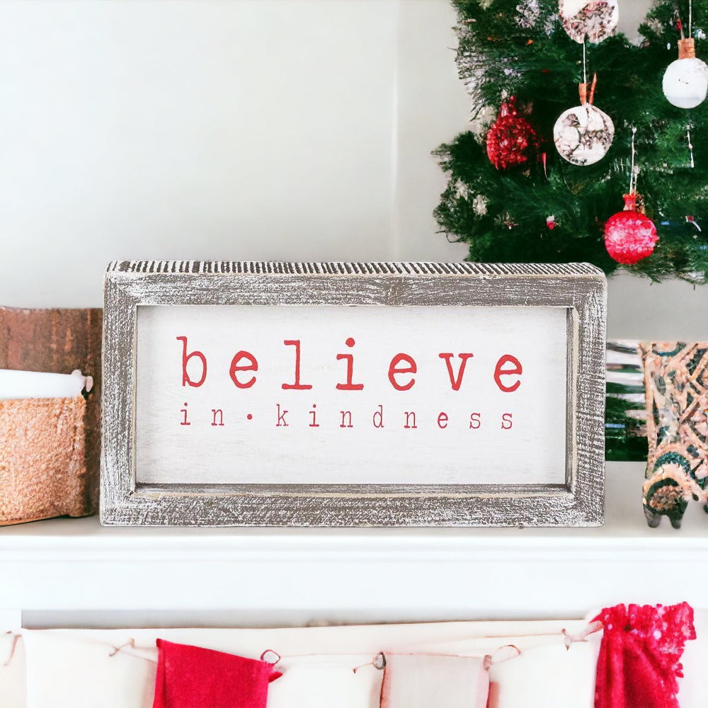 A wood framed Believe Sign featuring the phrase 'Believe In Kindness' in festive white and red colors, perfect for Christmas decor.