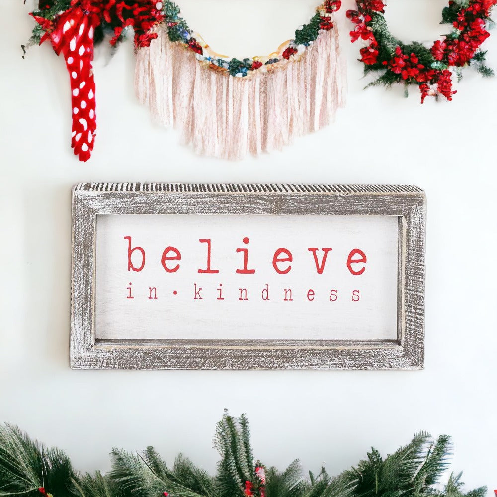 A wood framed Believe Sign featuring the phrase 'Believe In Kindness' in festive white and red colors, perfect for Christmas decor.