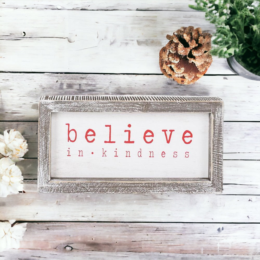 A wood framed Believe Sign featuring the phrase 'Believe In Kindness' in festive white and red colors, perfect for Christmas decor.