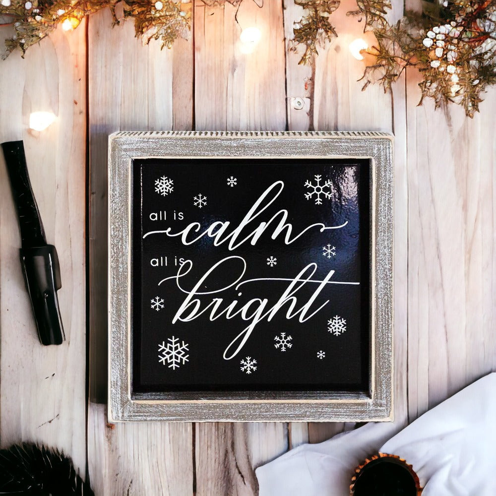 A stylish 7-inch wooden framed sign with embossed lettering that reads 'All is calm all is bright', perfect for holiday decor.