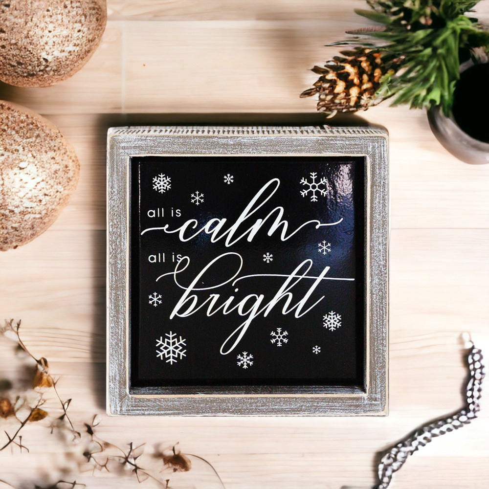 A stylish 7-inch wooden framed sign with embossed lettering that reads 'All is calm all is bright', perfect for holiday decor.