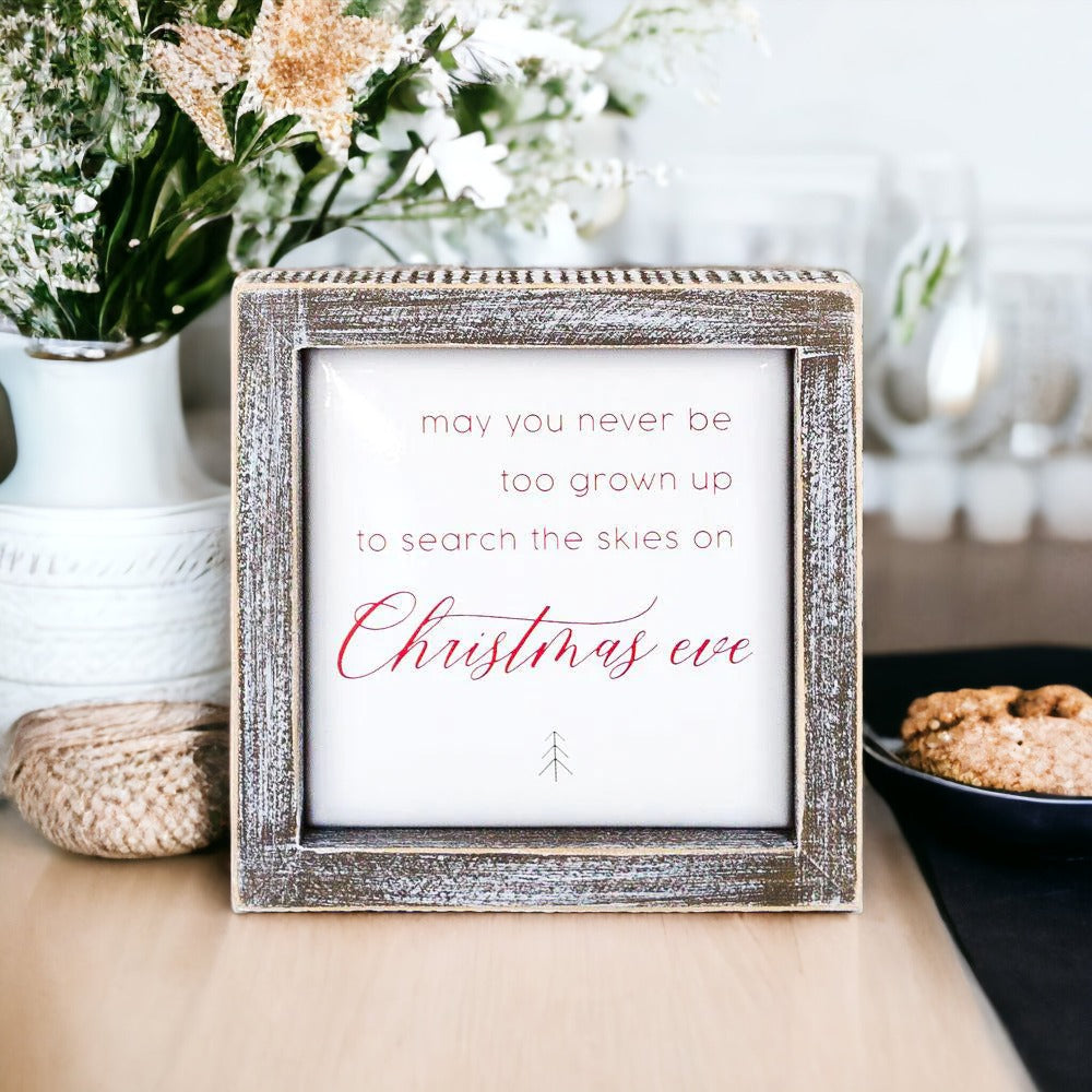 A beautifully crafted 5-inch wooden framed sign with metal embossed lettering that reads 'may you never be too grown to search the skies on Christmas eve'.