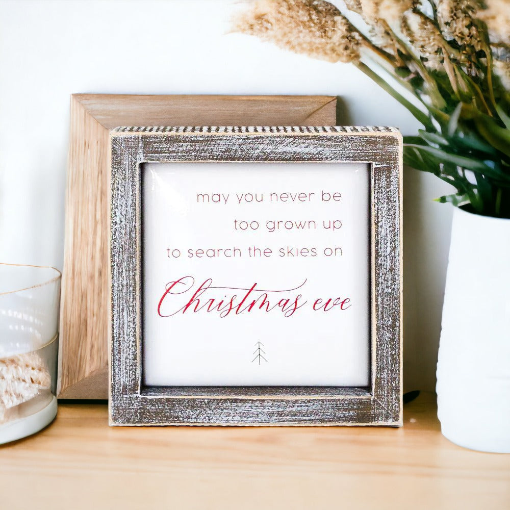 A beautifully crafted 5-inch wooden framed sign with metal embossed lettering that reads 'may you never be too grown to search the skies on Christmas eve'.