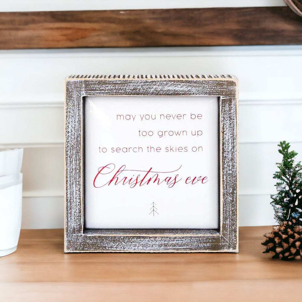 A beautifully crafted 5-inch wooden framed sign with metal embossed lettering that reads 'may you never be too grown to search the skies on Christmas eve'.