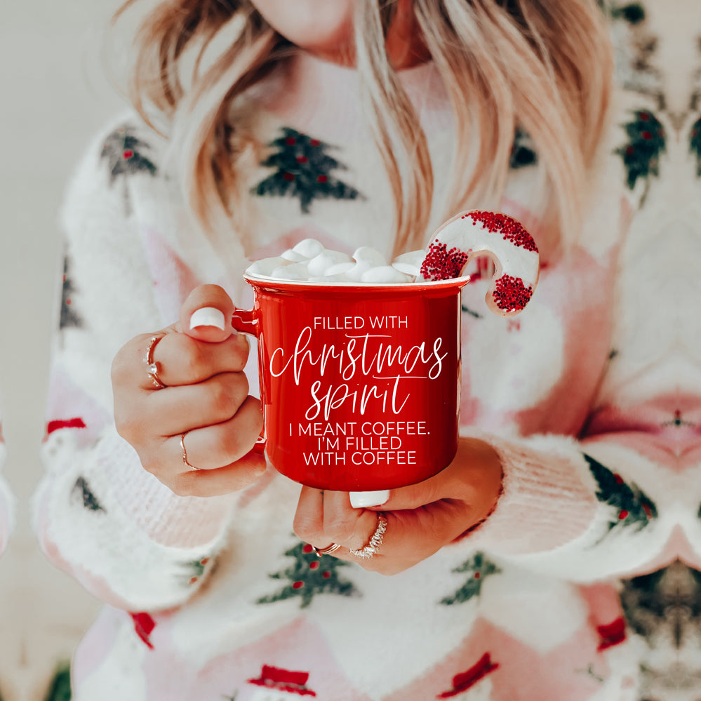 A festive Christmas Spirit Mug in red ceramic with white lettering, showcasing a cheerful design on both sides, perfect for holiday beverages.