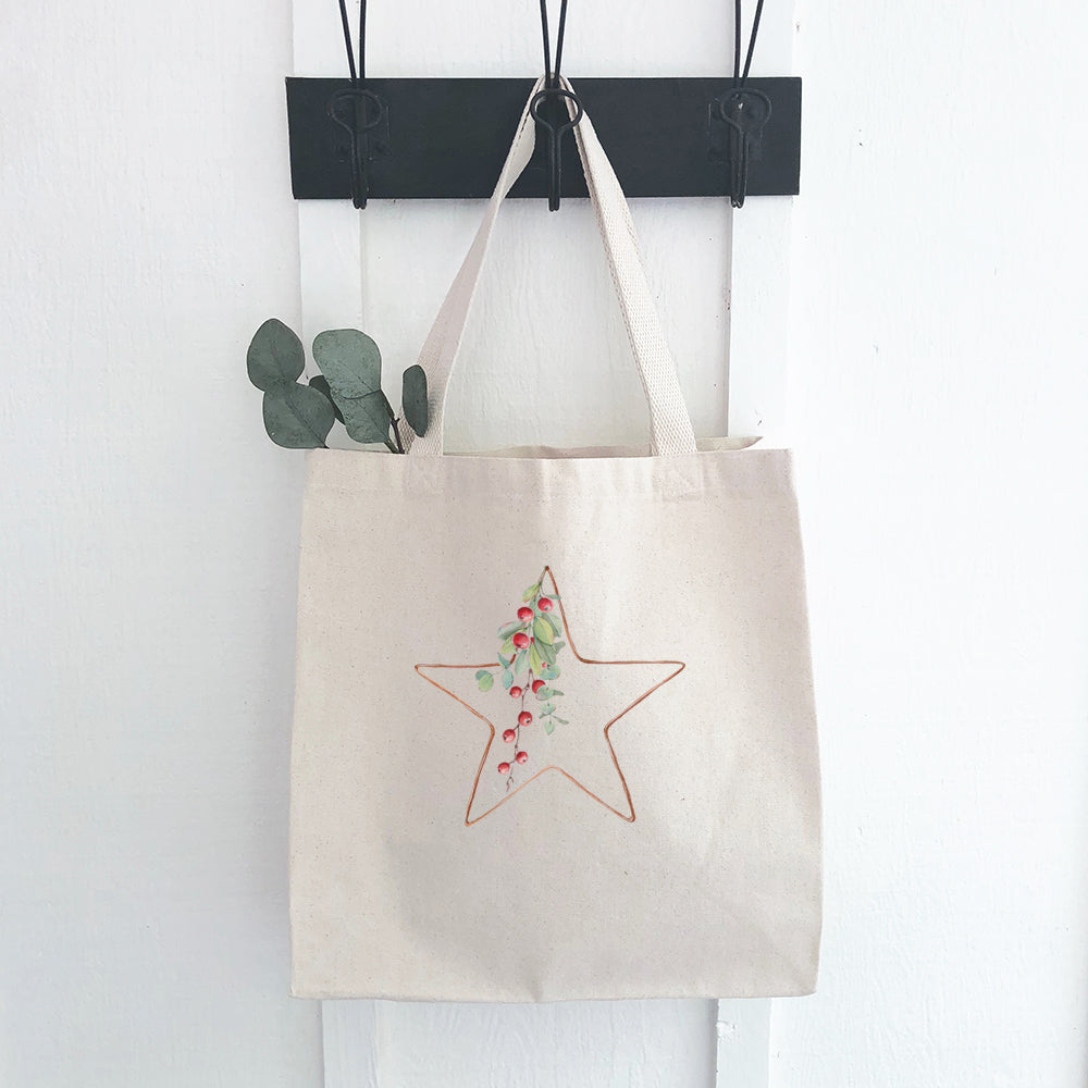 A festive canvas tote bag featuring a Christmas star design with berries, made from durable fabric with reinforced straps.