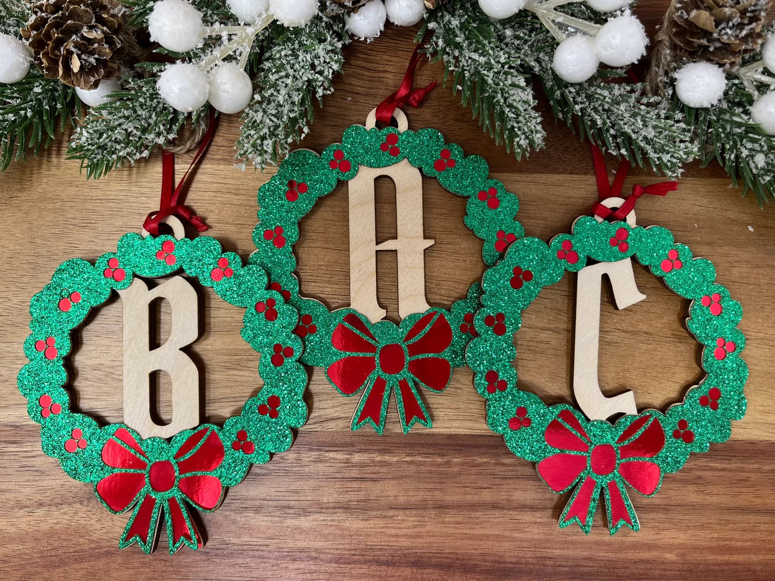 A beautifully crafted Christmas wreath monogram ornament made from premium Baltic Birch wood, featuring a festive ribbon for hanging.