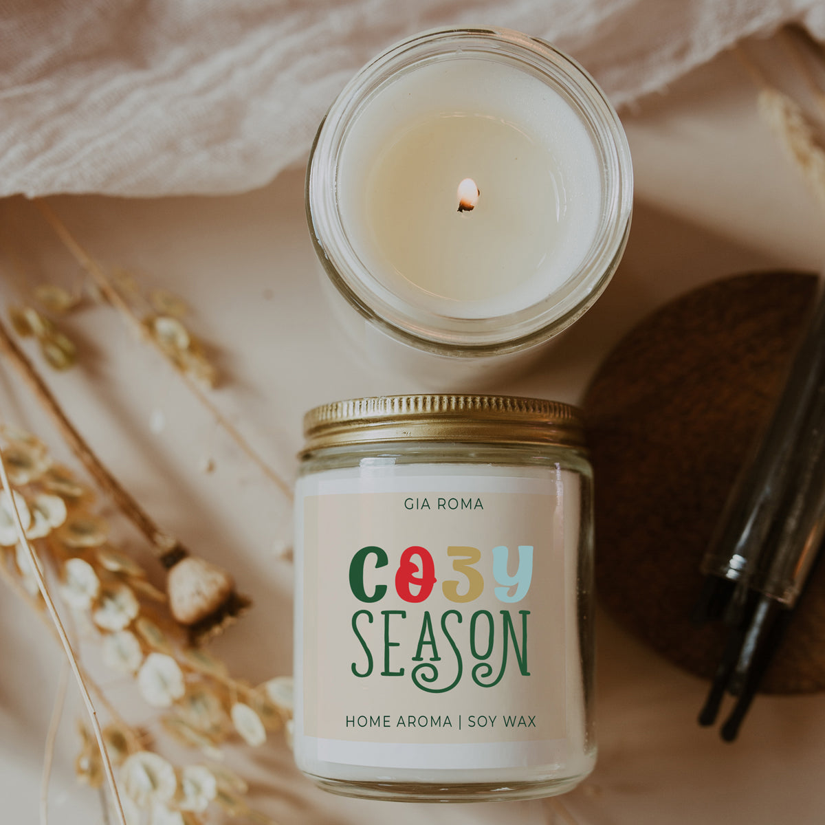 A beautifully crafted 9oz Cozy Season Candle with a warm glow, featuring a blend of winter scents like citrus, cloves, and pine cones.