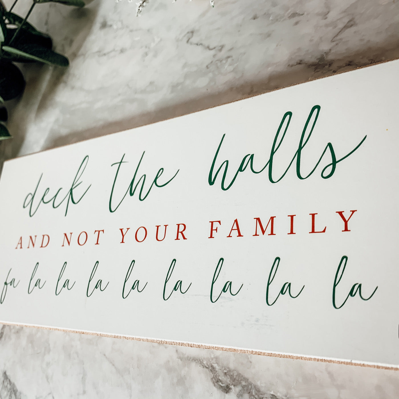 Handmade Deck The Halls Sign made of thick wood with a humorous Christmas quote in red and green, featuring a rustic textured area.