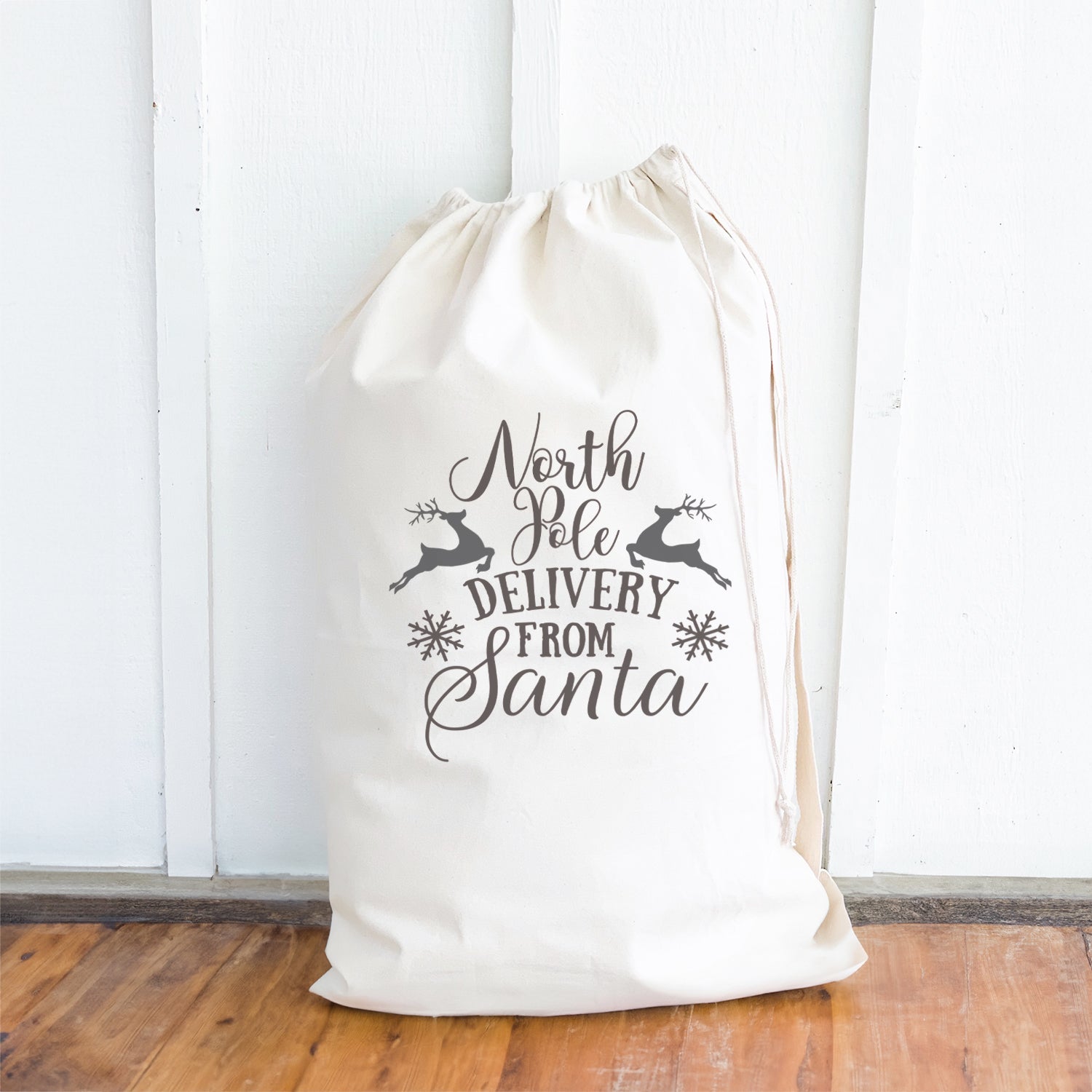 A festive Santa Sack made of heavy-duty canvas, featuring a drawstring closure and cotton webbing handle, perfect for carrying Christmas gifts.