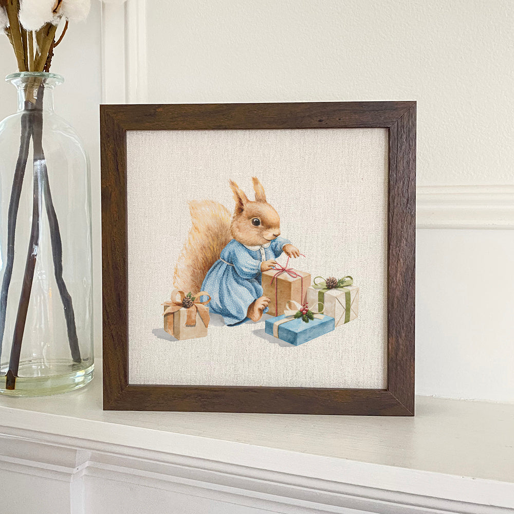 Framed sign featuring a whimsical squirrel with presents, set in a stylish wood frame.