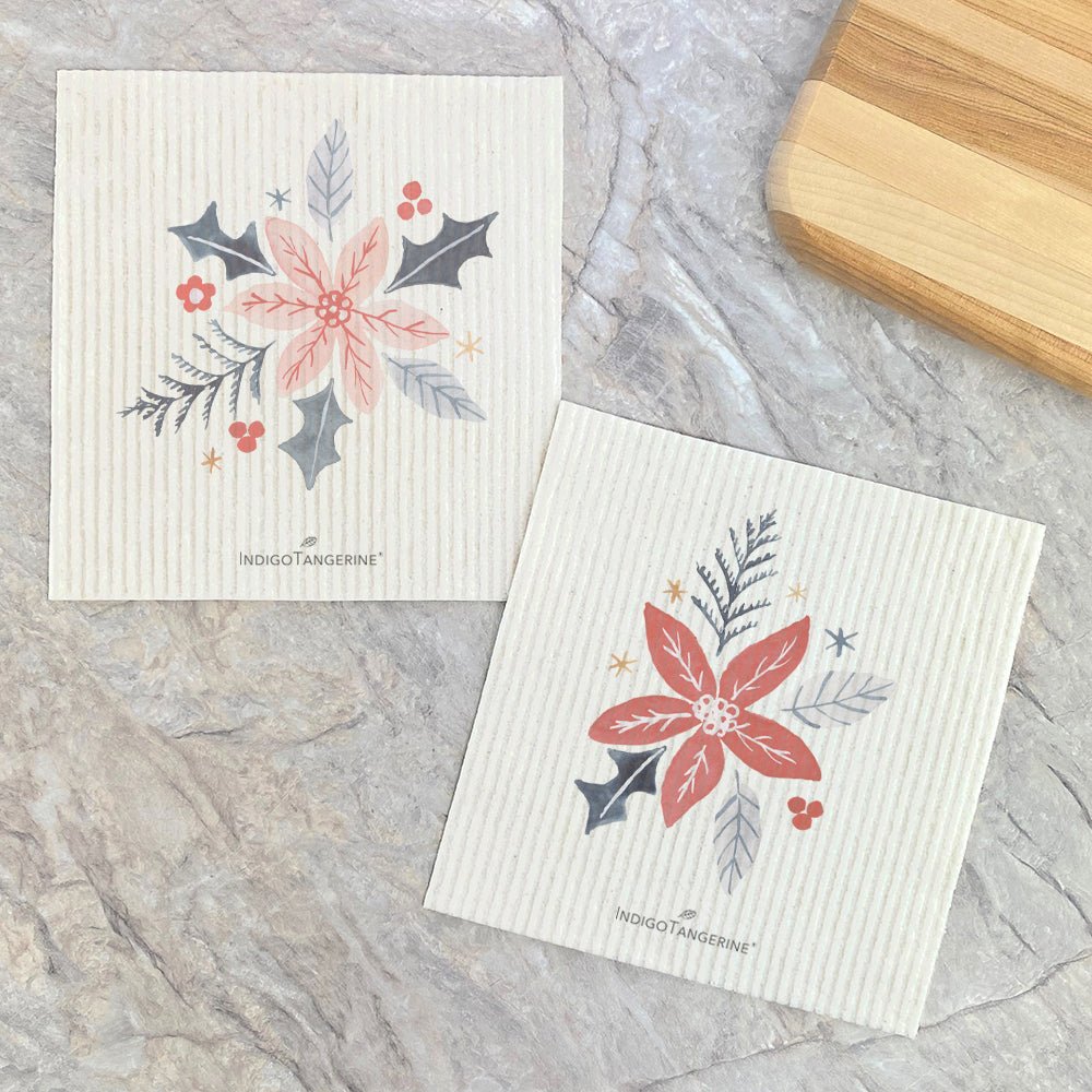 Two eco-friendly Swedish dish cloths featuring hand-drawn poinsettia designs, made from plant-based materials.