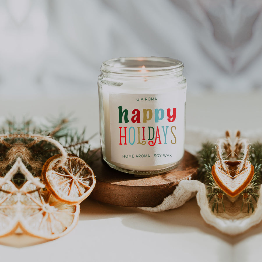 Happy Holiday Candle in a 9oz jar with festive scents of pine, orange, and woods, perfect for creating a cozy holiday atmosphere.