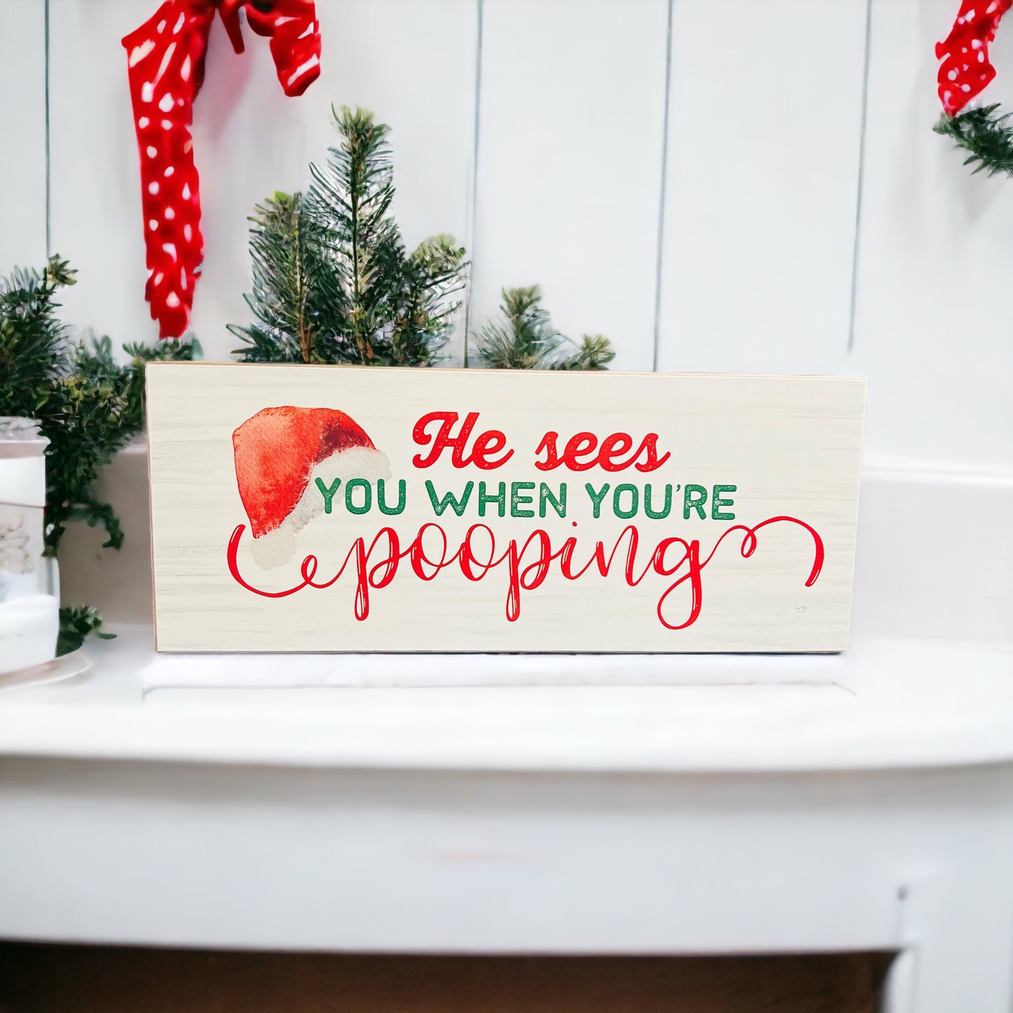 A whimsical wooden sign reading 'He sees you when you're pooping', perfect for Christmas decor, showcasing a humorous design.