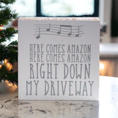 A charming wooden block sign that reads 'Here Comes Amazon' in neutral colors, perfect for home decor.