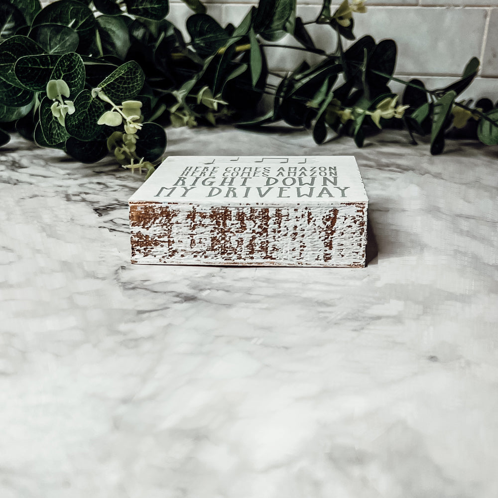 A charming wooden block sign that reads 'Here Comes Amazon' in neutral colors, perfect for home decor.