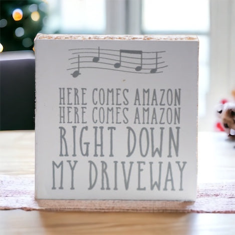 A charming wooden block sign that reads 'Here Comes Amazon' in neutral colors, perfect for home decor.