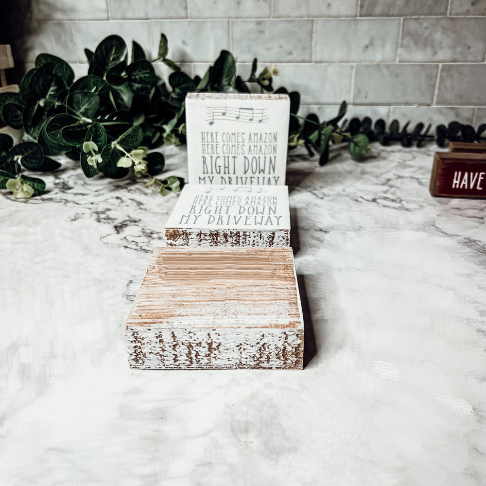 A charming wooden block sign that reads 'Here Comes Amazon' in neutral colors, perfect for home decor.