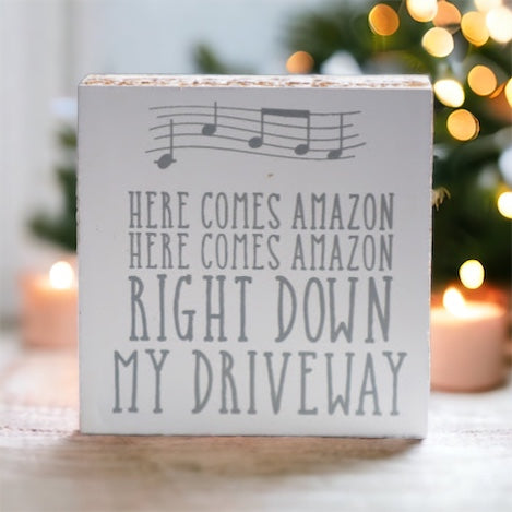 A charming wooden block sign that reads 'Here Comes Amazon' in neutral colors, perfect for home decor.