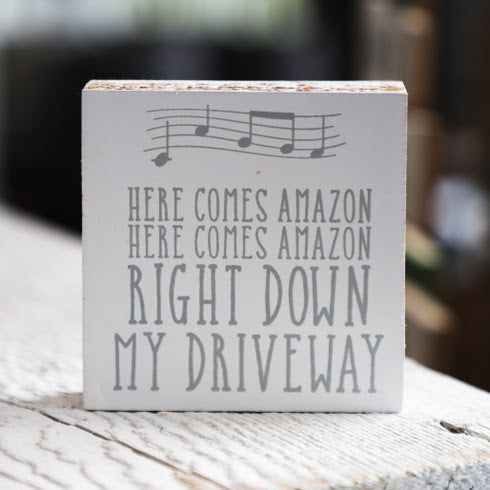 A charming wooden block sign that reads 'Here Comes Amazon' in neutral colors, perfect for home decor.