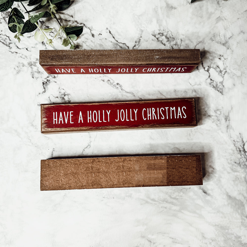 Holly Jolly Sitter Sign, a wooden block sign with festive lettering, perfect for holiday decor.