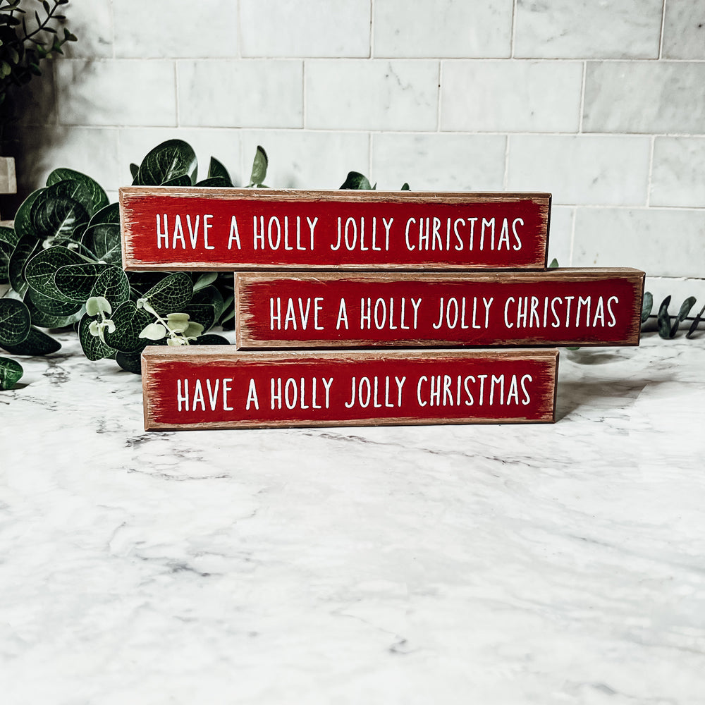 Holly Jolly Sitter Sign, a wooden block sign with festive lettering, perfect for holiday decor.